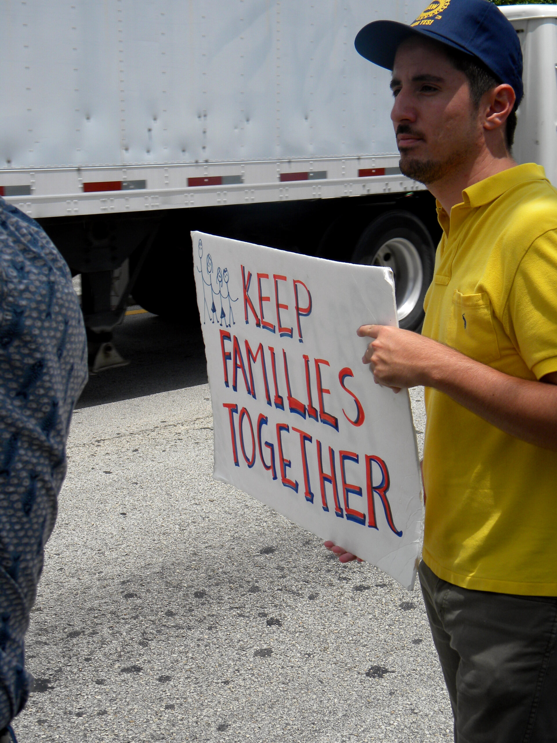 Protesters holding signs advocating for immigrants in front of a government building