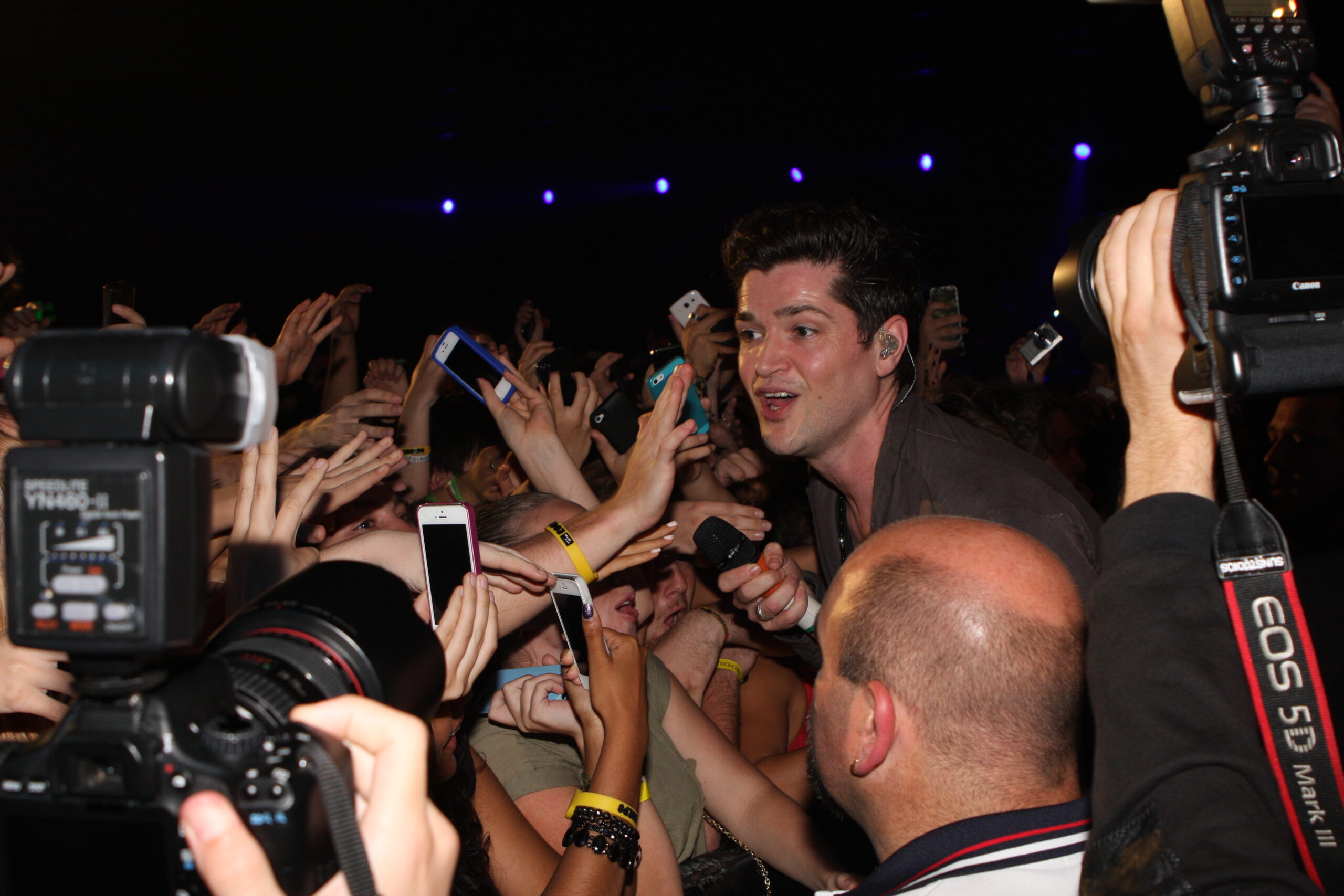 A band performing on stage; crowd illuminated by stage lights