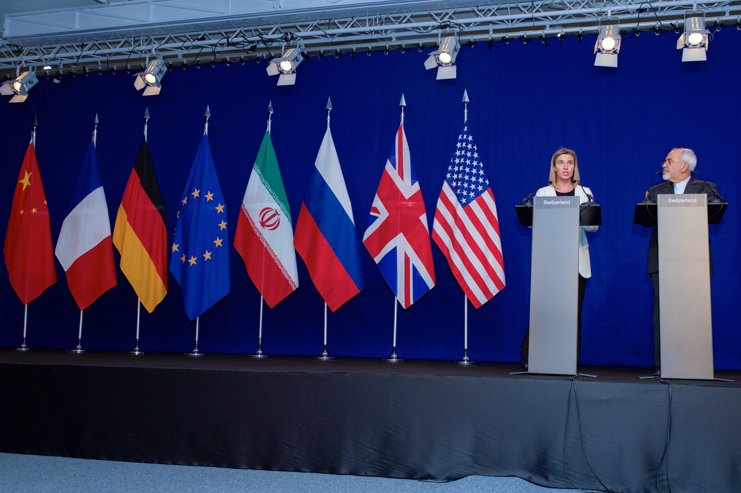 A diplomatic negotiation table with U.S., Israeli, and Lebanese flags visible