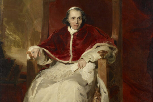 Portrait of a man in a red ceremonial robe and white garments, seated on a wooden throne before red drapery.