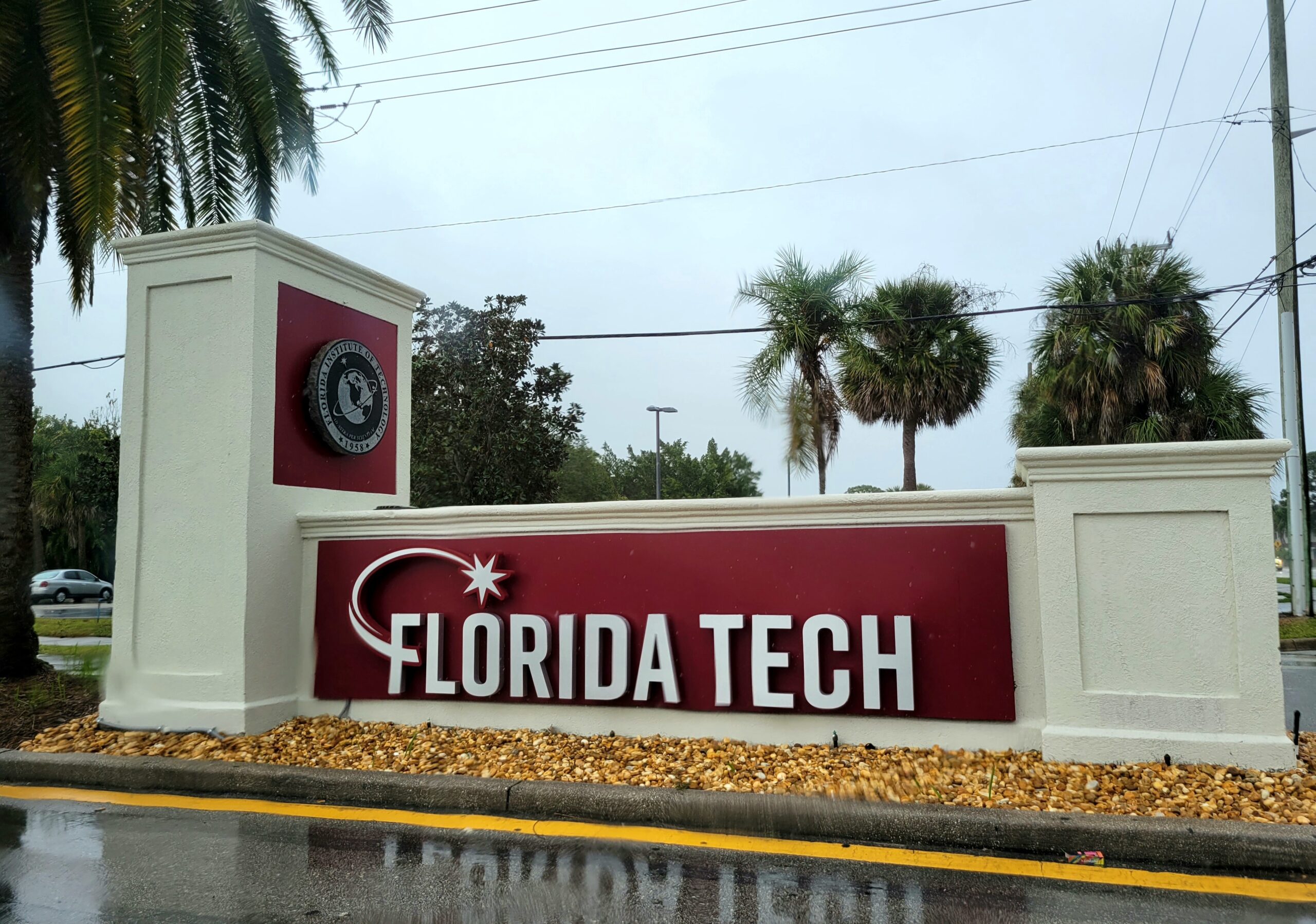 A close-up of a university building entrance showing signage alongside students walking nearby