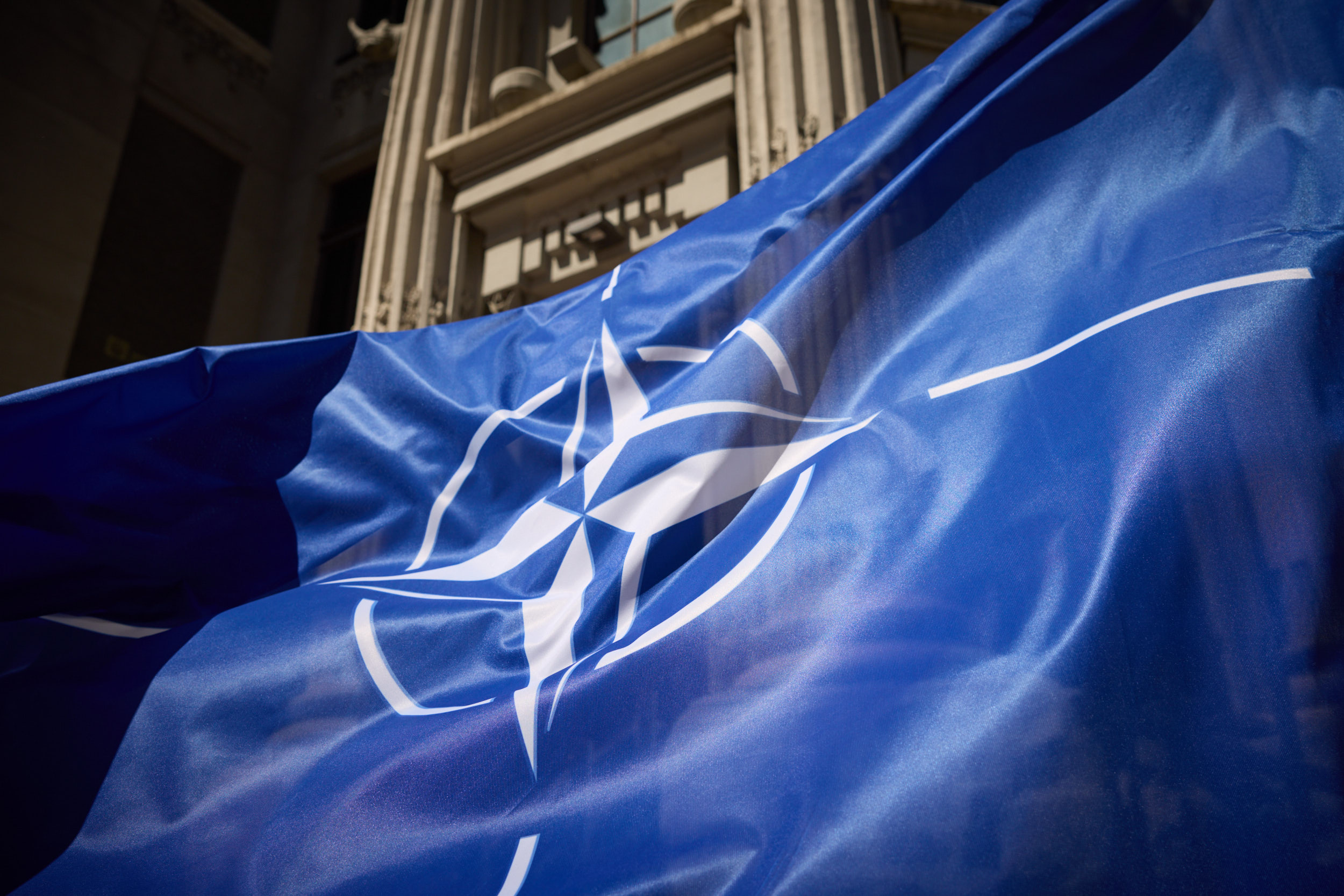 NATO leaders meeting in a conference room, showing flags of member states prominently